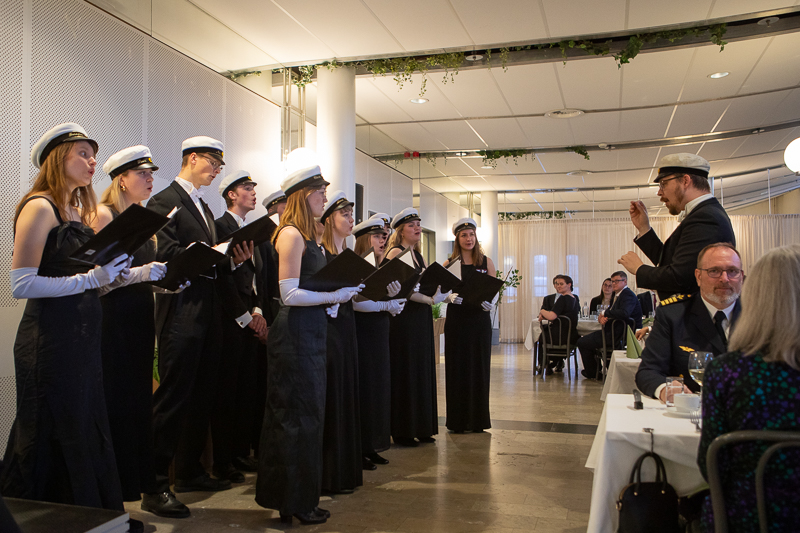 A student choir wearing black, students caps and white gloves entertained the guests during the dinner.