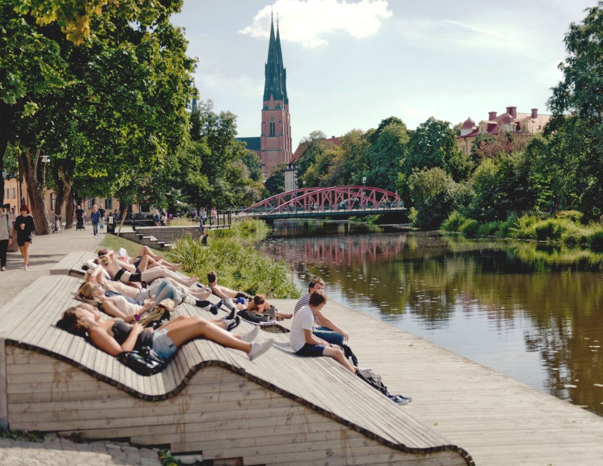 Några människor vilar vid ån i centrala Uppsala. foto