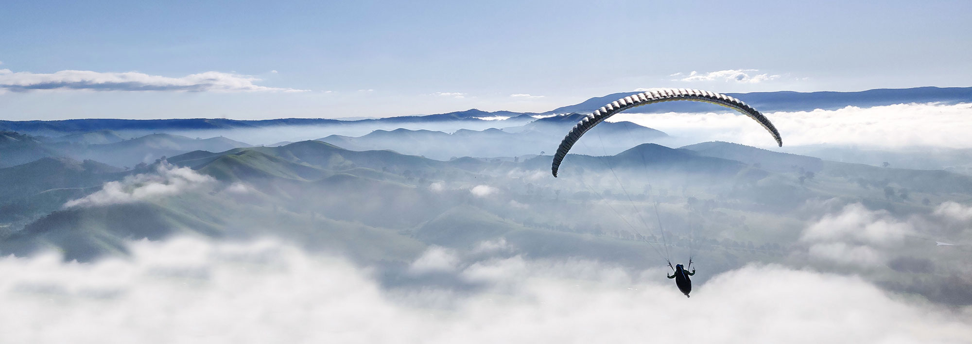 En skärmflygare högt över land och berg. Foto.