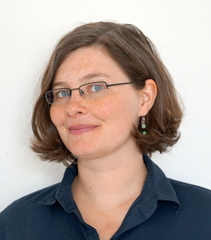 Porträttfoto av en leende kvinna med brunt hår, foto.
