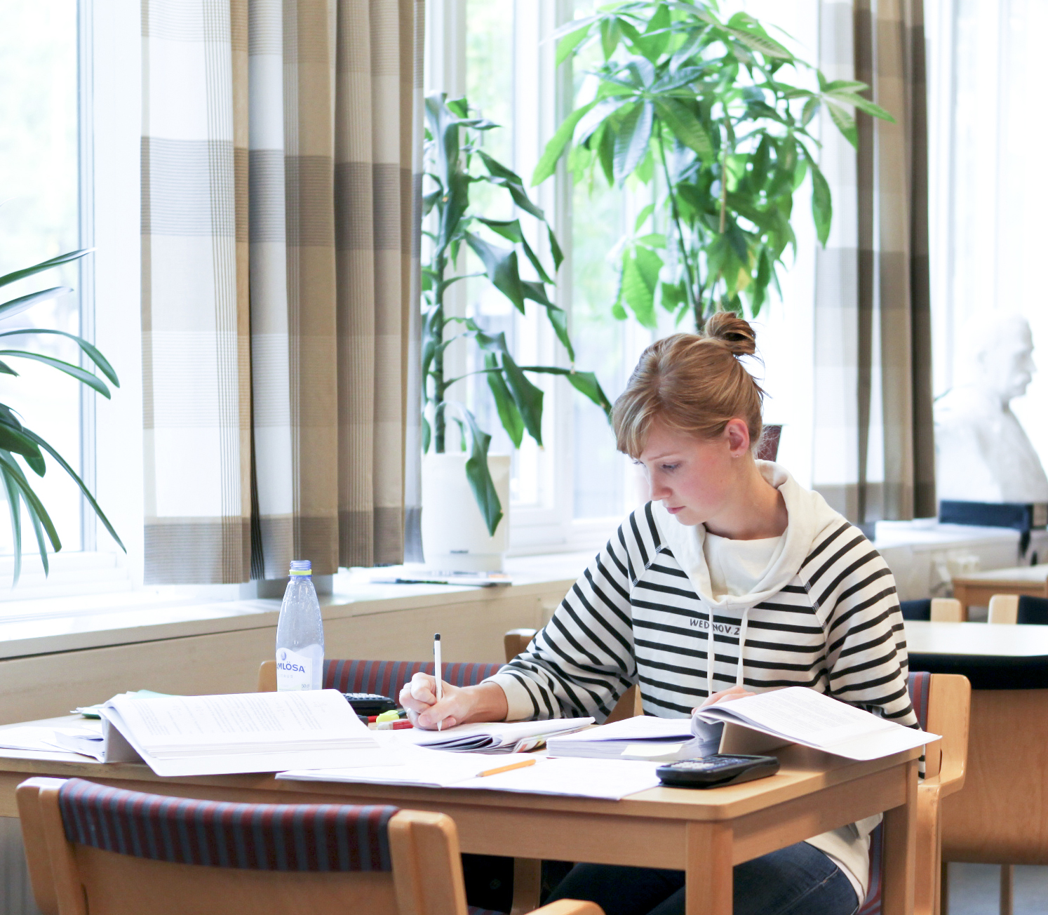 Kvinnlig student pluggar i biblioteket, foto.