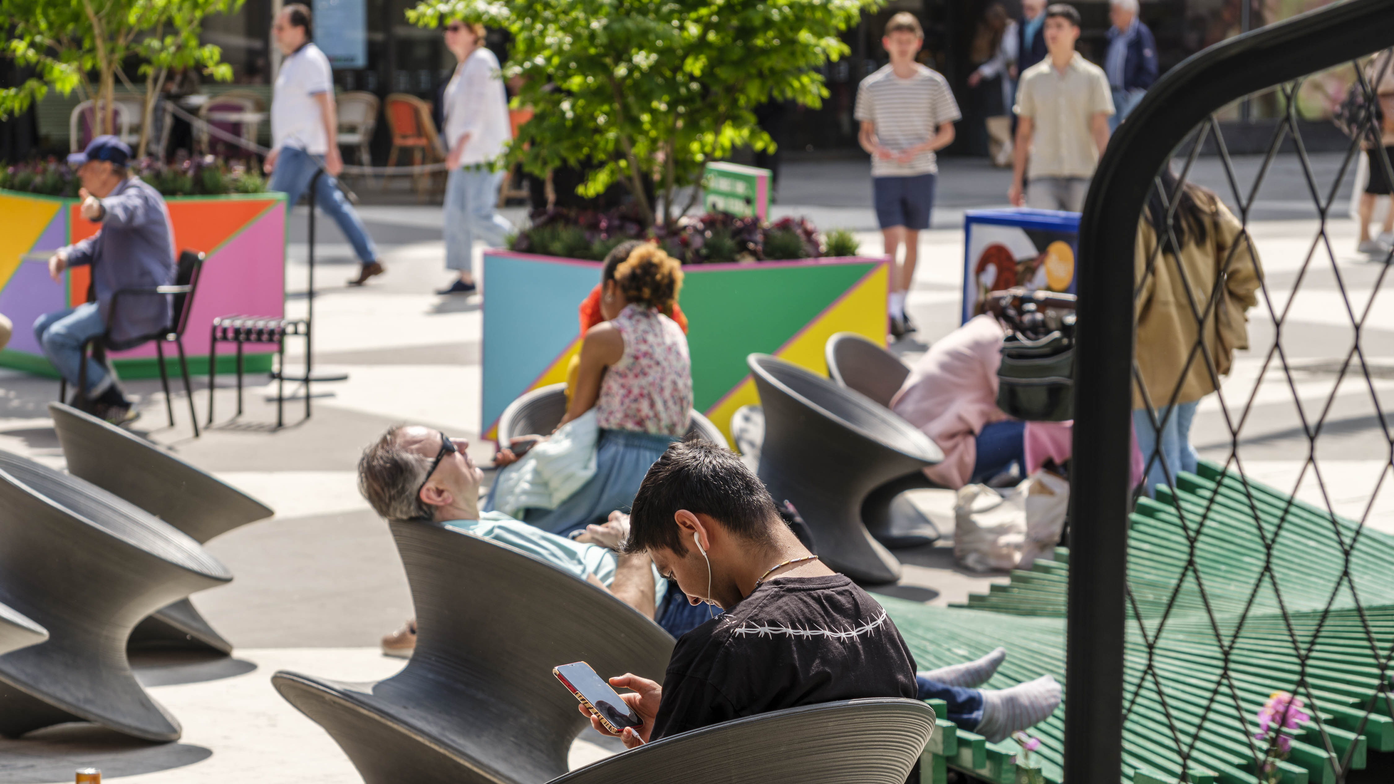 Några personer sitter och halvligger i sittmöbler på Sergels torg