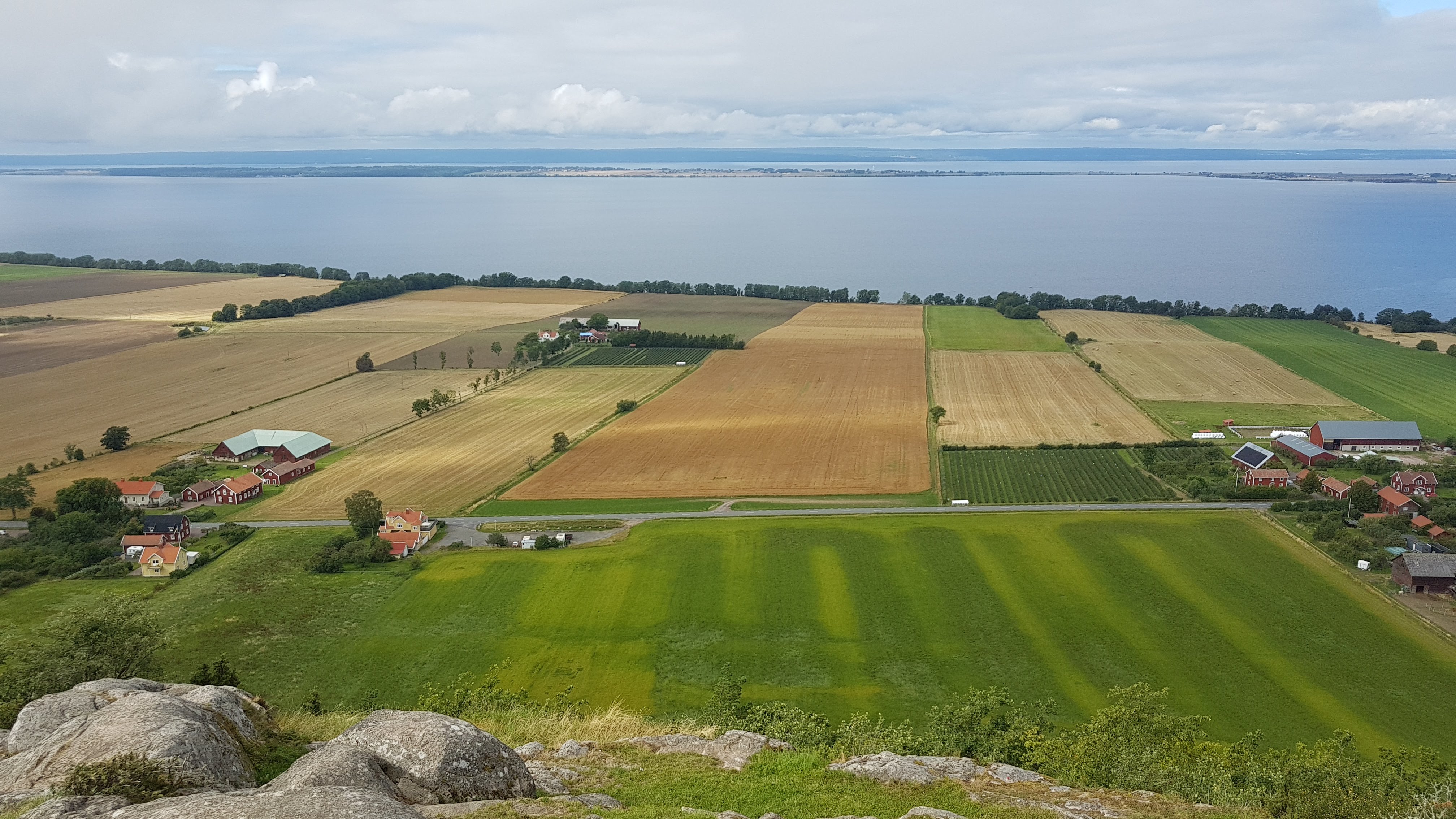 A landscape with fields and water in the background.