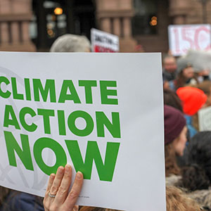Någon håller upp en skylt med texten "Climate Action Now" i ett hav av människor