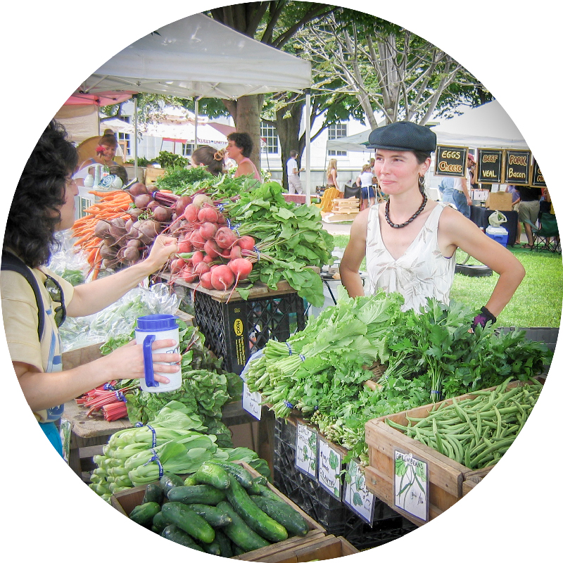 Two women at a farmers' market outdoors. Photo.