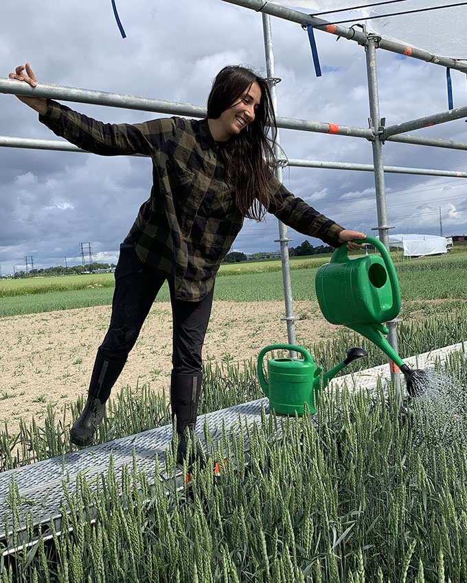Kvinna vattnar med grön vattenkanna.