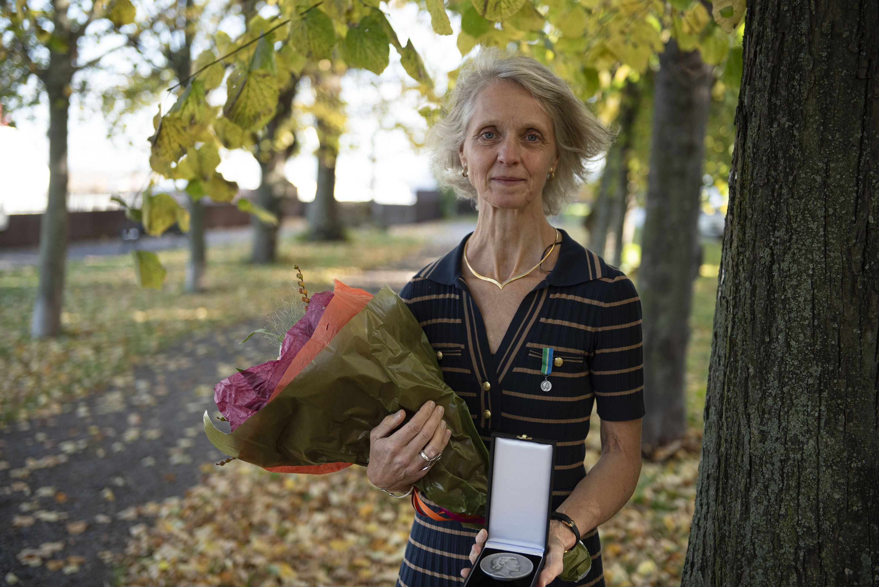 Helena Röcklinsberg visar upp sin medalj och håller en bukett med blommor.