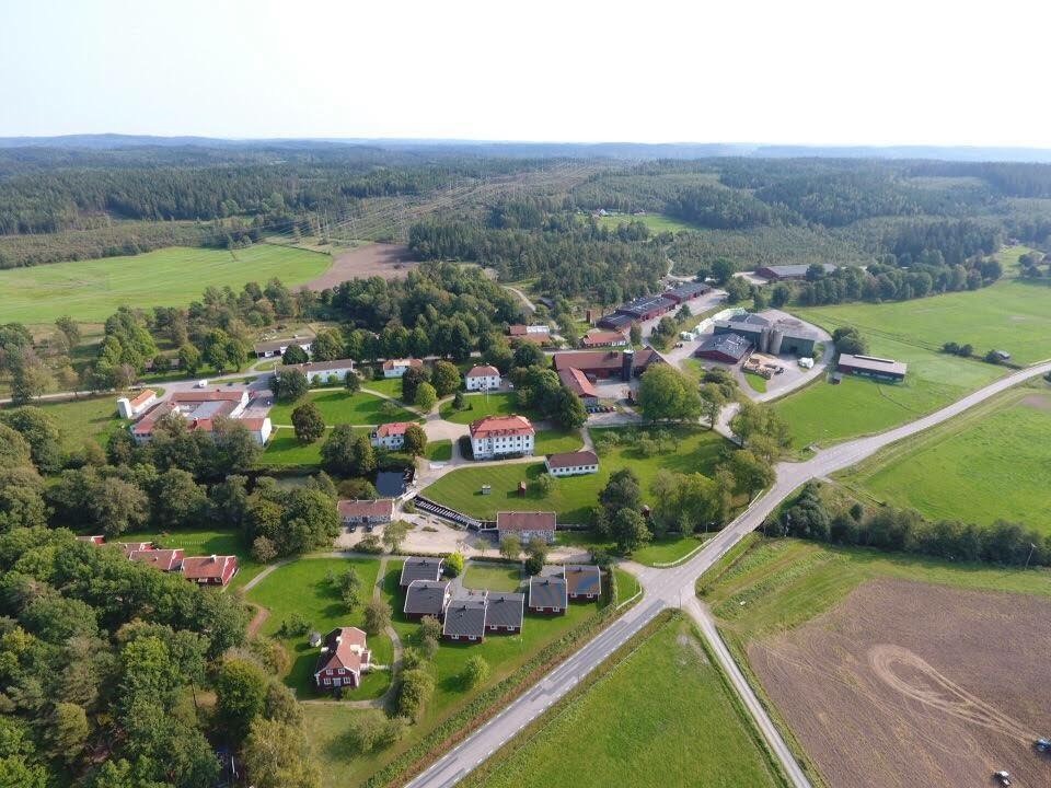 Flygbild över Strömma Naturbrukscentrum, byggnader, skogspartier och åkrar.