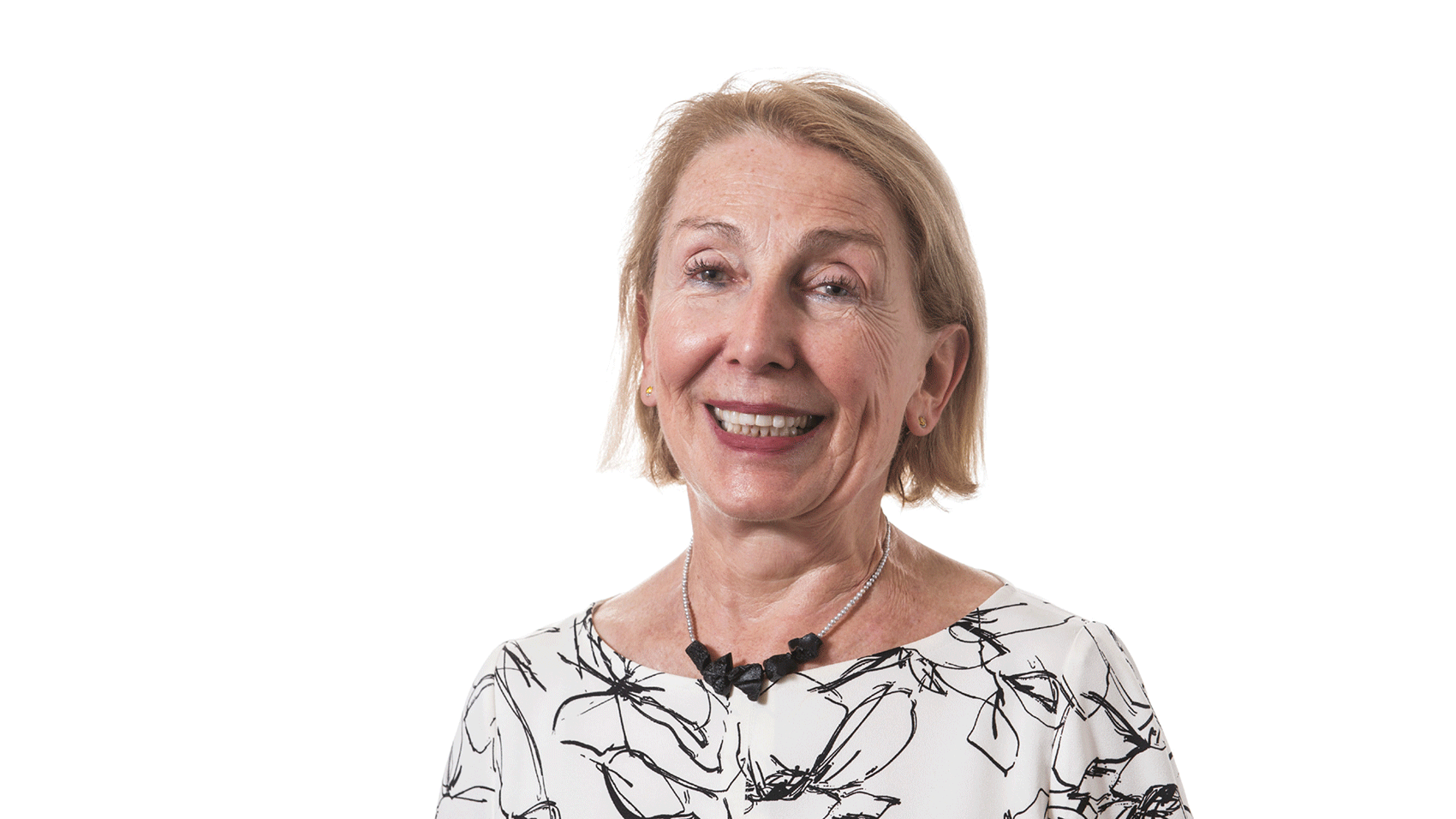 A woman wearing a blouse with a white and black pattern smiling.