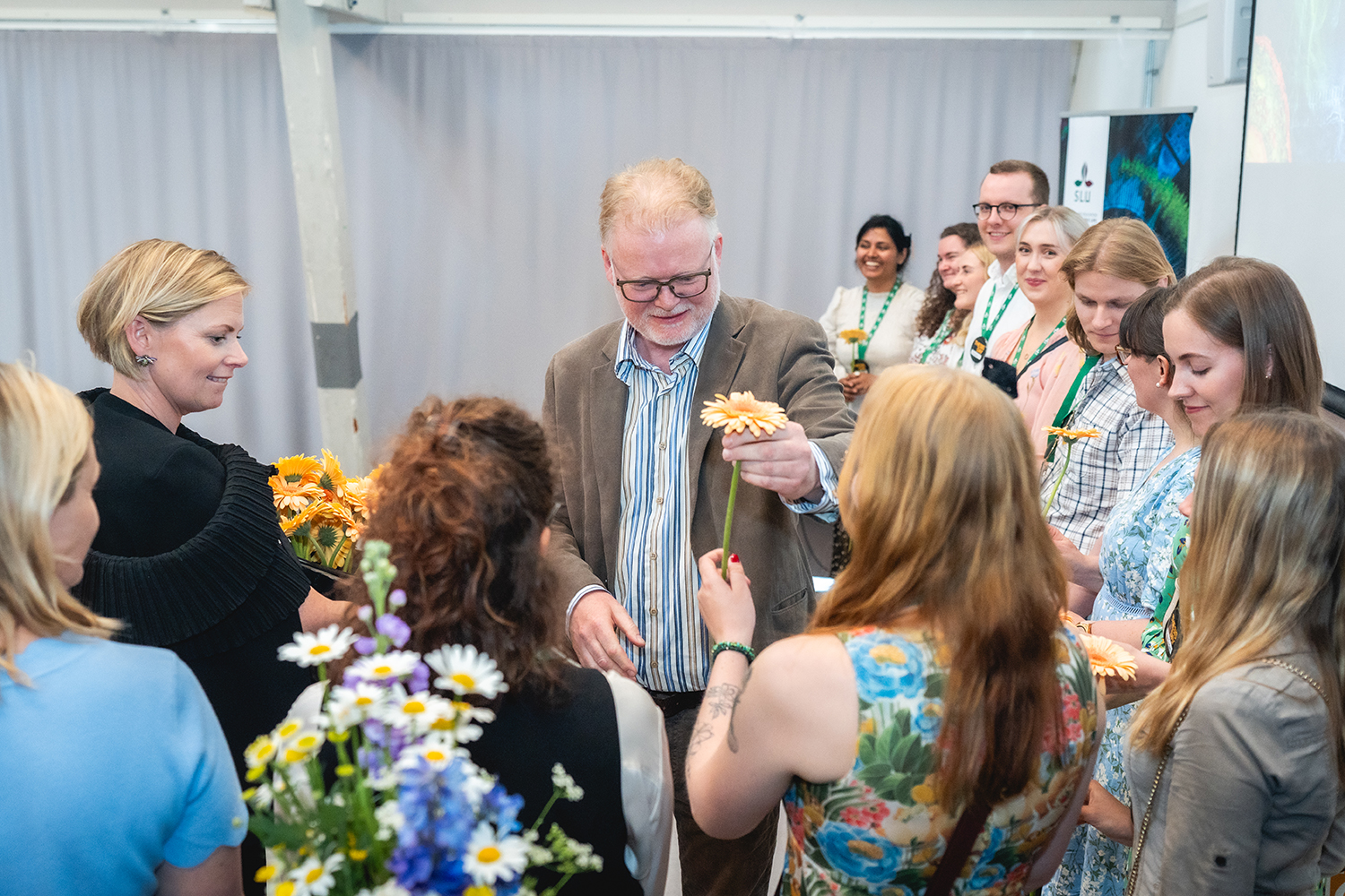 Karl Lövrie delar ut blommor till deltagarna på Thesis Day. Fotograf Joe Miller